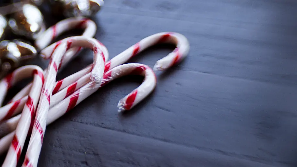 Zuckerstangen und kleine Glöckchen auf dunklem Holz